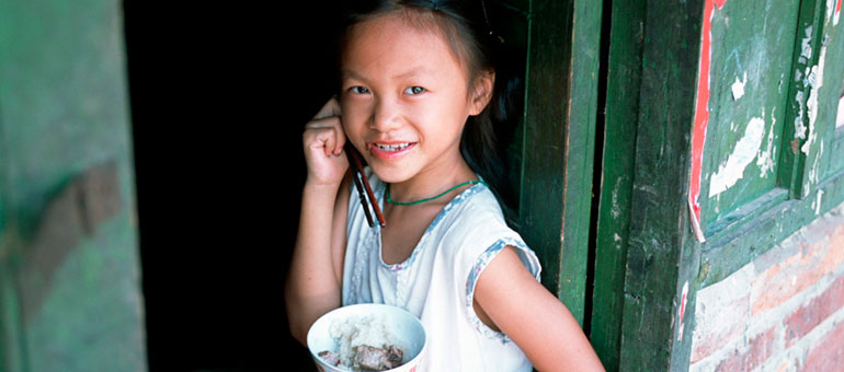 Chinese girl eating from a bowl against green door