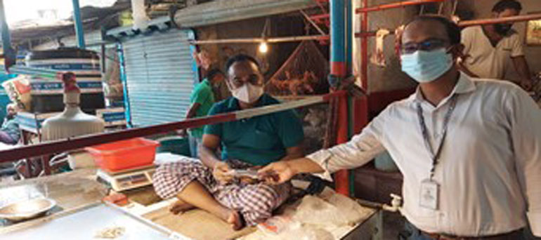 Dhaka food market - a vendor shaking hand with man wearing mask