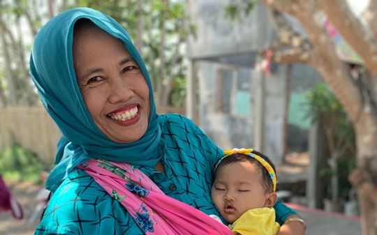 Mother holding sleeping baby and smiling in Indonesia