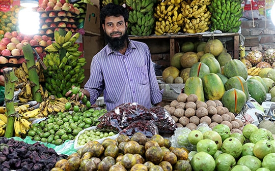 Man selling fruits and vegetables in an indoor market in Bangladesh