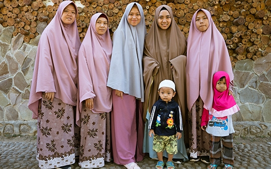 Women in hijabs and two small children standing in a line posing for a picture