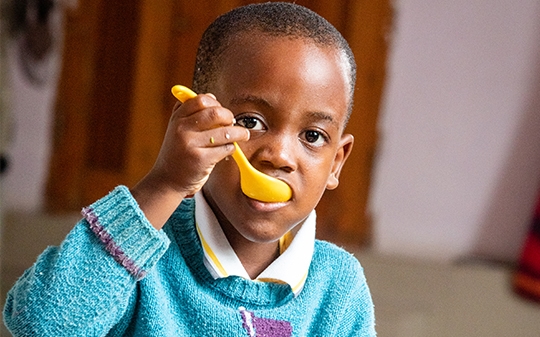 a child eating with a yellow spoon