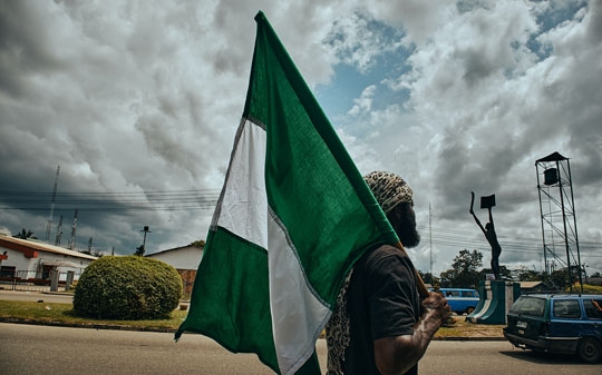 Nigerian man carrying the national flag in the street