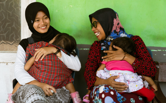 Two ladies carrying a baby