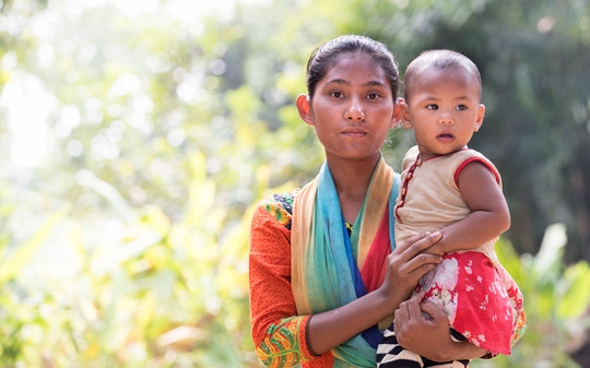 Young girl holding a baby and looking at the camera in Bangladesh