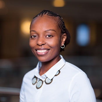 Grace smiling warmly to the camera while wearing a white shirt and necklace